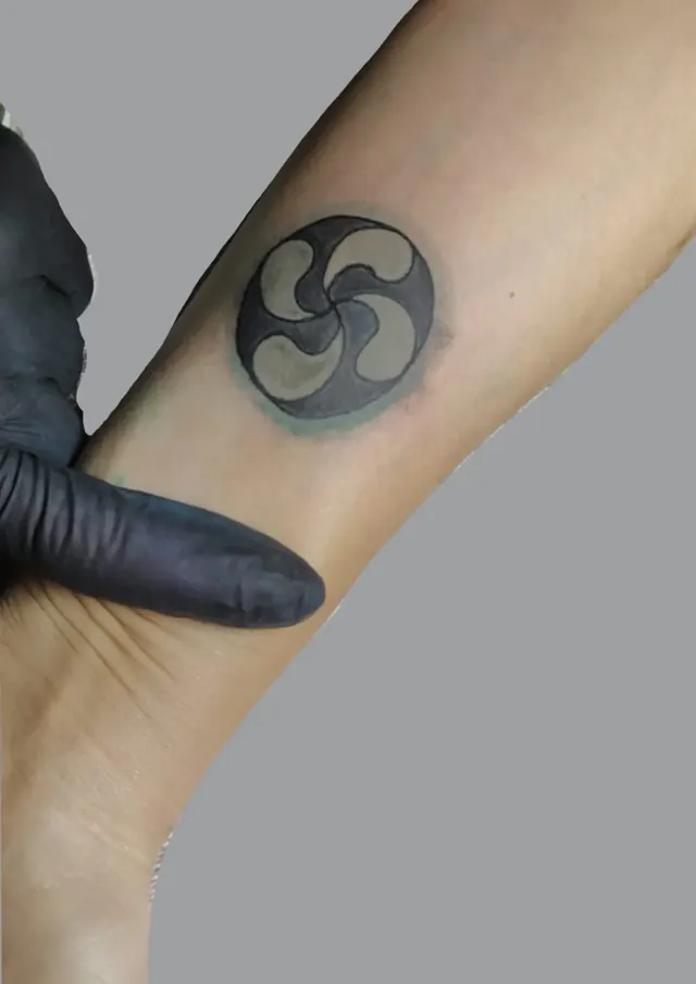 Tatouage d'un lauburu, croix basque, dans un cercle